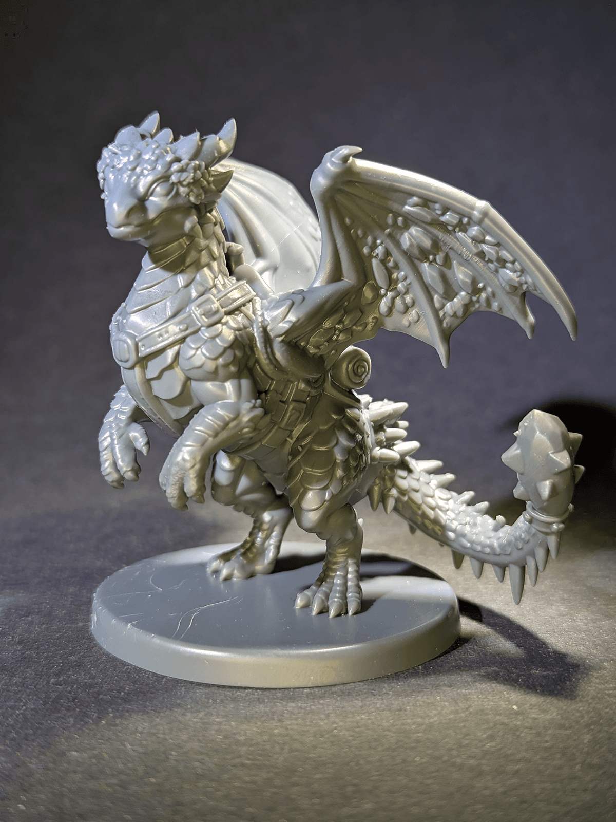 Unpainted resin dragon mount miniature with wings and a saddle on a round base